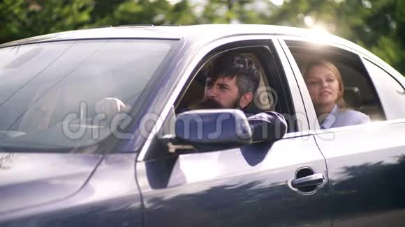 长胡子的男人和金发女郎坐在蓝色的车里夫妻俩开着车去避暑视频的预览图