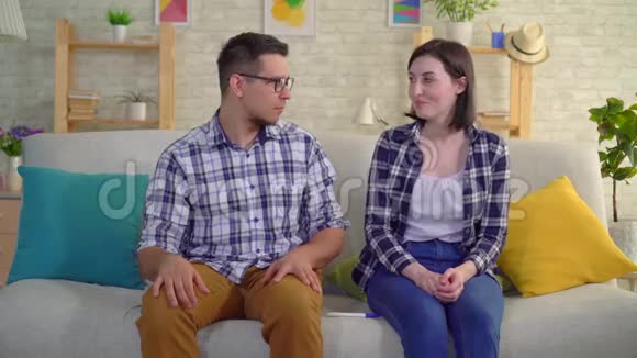 年轻而失望的夫妇坐在客厅里得知怀孕测试为阴性视频的预览图