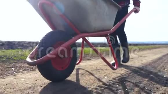 农民女孩红脖子在泥土里工作带着一辆花园式生活手推车穿着橡胶靴农民生态农业视频的预览图