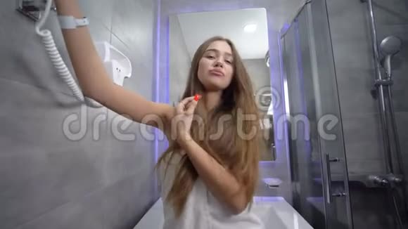 一位穿着毛巾的漂亮长发的迷人女性在浴室里享受着乐趣在相机上摆姿势积极地和一个视频的预览图