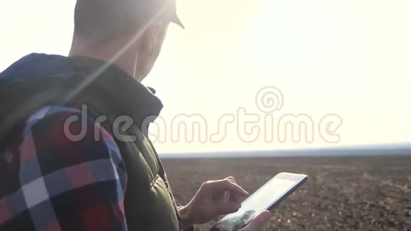 男子农民红脖子与数字平板行走在土地上为缝纫生活方式在土壤黑田生态农业视频的预览图