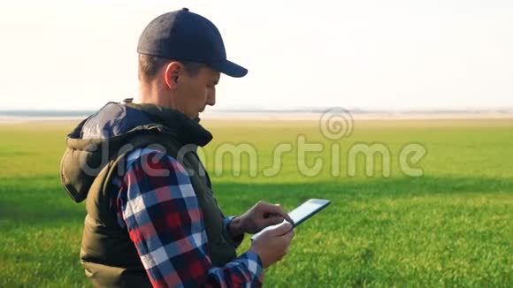 男人农民红脖子与数字平板走在绿色的田野生态智能农业生活方式概念男性视频的预览图