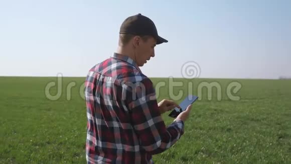 男子农民红脖子与数字平板行走在土地上播种在绿色的田野生态农业概念视频的预览图