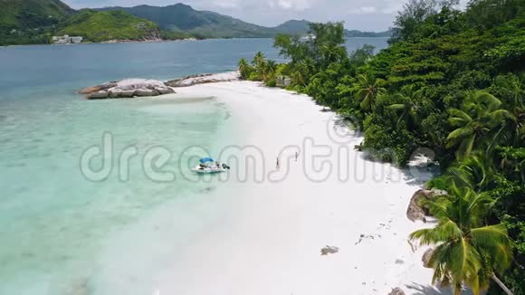 在热带异国海滩上乘船游览情侣的空中4k景蓝色泻湖有清澈的蓝色海水和视频的预览图