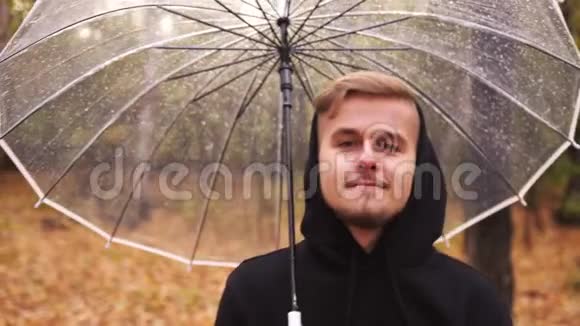 一个年轻人在雨天沿着秋天公园散步的肖像视频的预览图