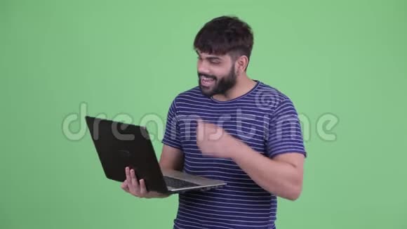 快乐的年轻超重胡须印度男子视频电话笔记本电脑视频的预览图