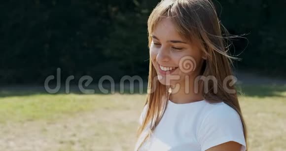 年轻迷人的女性的肖像她微笑着看着绿色草坪上的相机快乐的年轻女孩关门视频的预览图