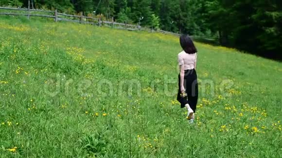 美丽的女孩走在绿色华丽的草坪上晴朗的夏日背景中的森林慢动作视频的预览图
