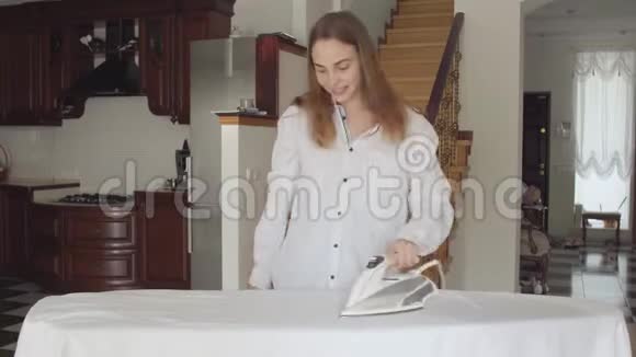 漂亮的年轻女人在家做家务时跳舞积极积极的家庭主妇熨烫衣服视频的预览图