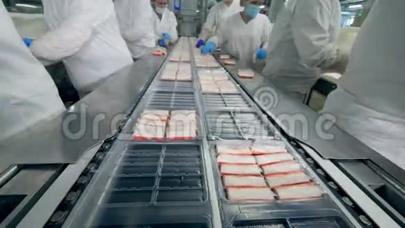 食品厂工人将产品放入输送机上的塑料容器中视频的预览图