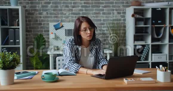 一个疲惫的女孩在办公室工作然后在工作中伸展手臂放松视频的预览图