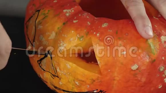 准备在万圣节制作灯笼手在木桌上的橙色南瓜上为鼻子切一个洞视频的预览图