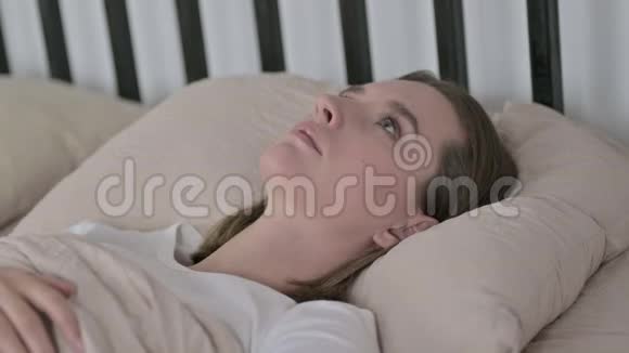 失眠的年轻女性躺在家里的床上视频的预览图