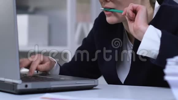 在笔记本电脑上工作的女人嚼着铅笔紧张的工作特写带来的坏习惯视频的预览图