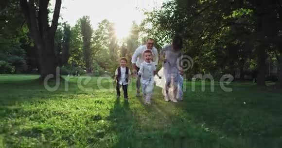 充满魅力的大家庭三个孩子在公园中央的摄像机前奔跑微笑着大大的视频的预览图
