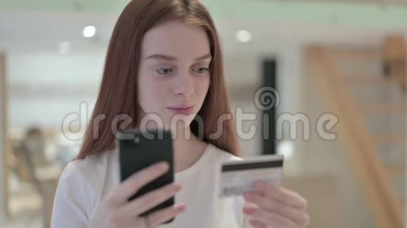 红发青年女性在智能手机上进行网上支付的画像视频的预览图