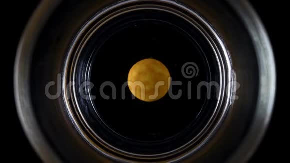 橙色巧克力纽扣溶解在水玻璃中的时间间隔视频的预览图
