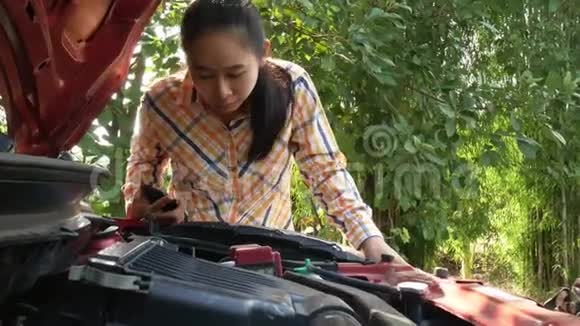 亚洲年轻女子试图在街上修理这辆破车视频的预览图