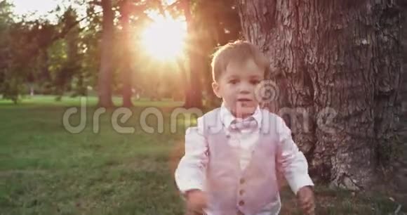 在一个大公园里镜头前的特写镜头里跑着一个小男孩笑容满面直视着镜头视频的预览图