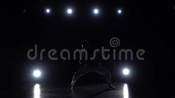 运动男在黑暗中练习卡波伊拉对抗演播室的聚光灯视频的预览图
