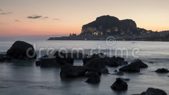 意大利西西里岛城市头孢卢日出时的时间流逝海水和岩石在前景中视频的预览图