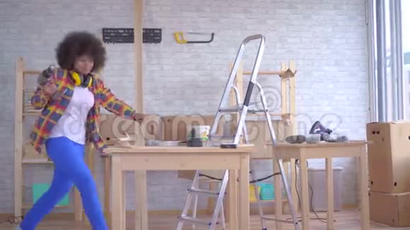 有非洲发型的有趣跳舞的非洲女人在车间的木头上工作视频的预览图