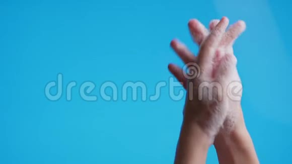 双手在蓝色背景上用肥皂泡沫洗手近距离拍摄预防covid19细菌保健视频的预览图