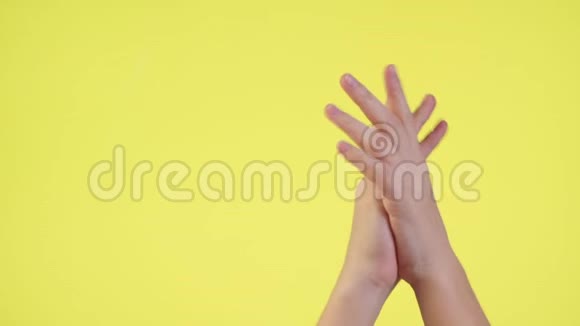 女人的双手交叉着手指等待着特殊的时刻让愿望在黄色的背景上被隔离视频的预览图