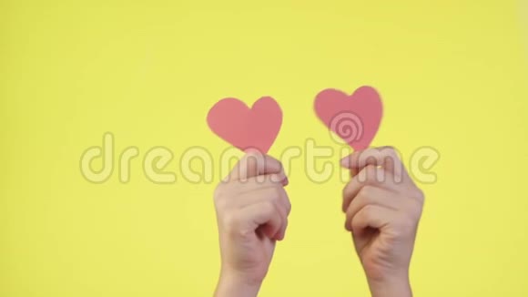 雌性手中握着黄色背景上孤立的小红心社交网络柔情的概念情人节视频的预览图