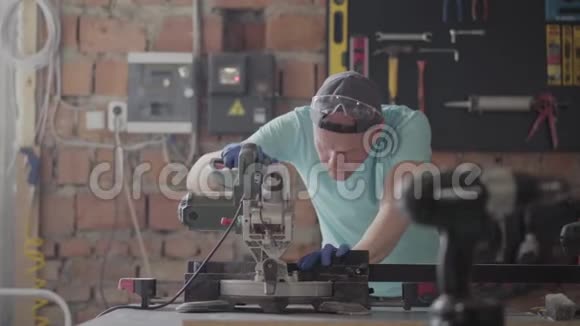 肖像技术工艺员在保护眼镜上切割木板桌上放着一个小圆锯视频的预览图