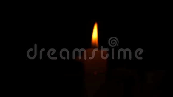 平静的橙色蜡烛火焰在黑暗的背景下近距离观看视频的预览图