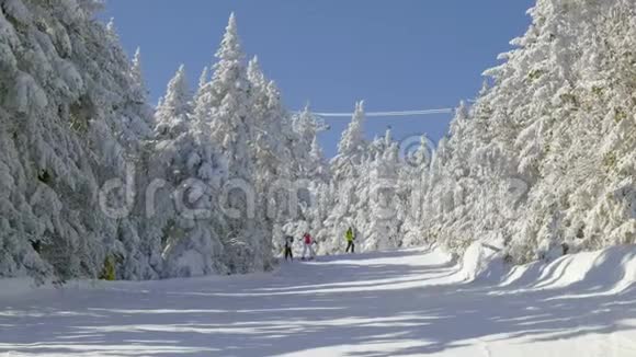 滑雪者在斜坡和滑雪升降机与雪覆盖的树木椅子升降机背景视频的预览图