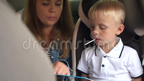 母亲和儿子正在汽车后座上看书视频的预览图