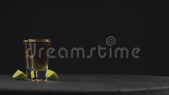 两杯金色龙舌兰在黑色背景上旋转的黑板上粗盐落在龙舌兰的上面酗酒者视频的预览图
