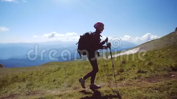 年轻女子带着背包和徒步旅行杆走上山顶慢动作女士在美丽的地方徒步旅行视频的预览图