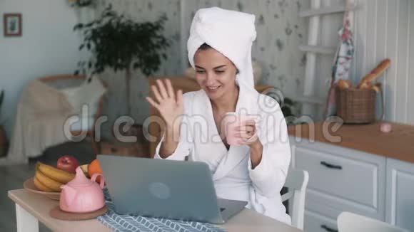 穿白色浴袍的女孩头上有毛巾手提电脑上有视频聊天慢动作视频的预览图
