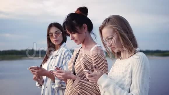 友谊技术和互联网概念三个年轻妇女与智能手机户外视频的预览图