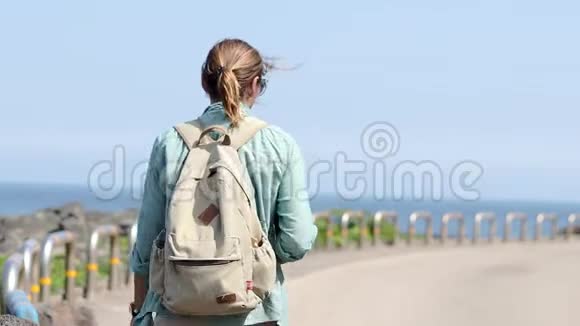 年轻的女游客带着背包走在路上可以看到海景视频的预览图