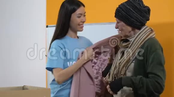 年轻的女志愿者为贫穷的无家可归的微笑妇女送冬衣视频的预览图