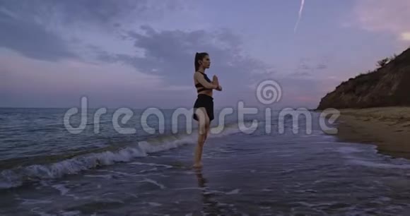 海滩侧景与海上瑜伽冥想姿势的女士站在水里集中有瑜伽时间视频的预览图