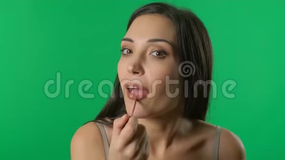 女人涂口红照镜子唇妆贴紧女孩在绿色屏幕背景下化妆铬视频的预览图