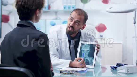 现代研究机构的医生在平板电脑上向病人显示X射线扫描视频的预览图