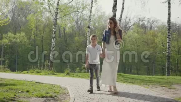 妈妈和儿子在神奇的绿色公园散步户外娱乐活动视频的预览图