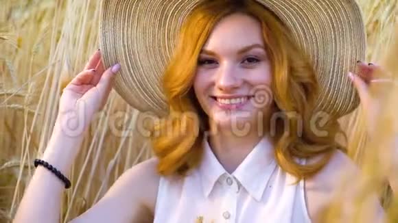 一位戴着大草帽的红发美女在麦田里对着镜头微笑视频的预览图