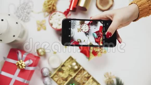 女人在智能手机上拍漂亮的照片女性手在白色桌子上拍照圣诞礼物垂直视频的预览图