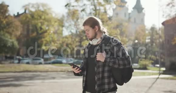 严肃的成年人在街上用智能手机走路有魅力的大胡子男人沿着城市的街道走视频的预览图