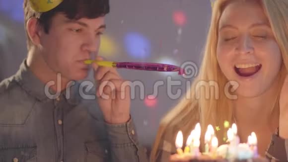 金发的微笑女孩和一个戴着生日帽的男人坐在小蛋糕前面拿着蜡烛女人过生日视频的预览图