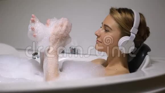 戴耳机的女性在洗澡时玩泡沫泡泡听舞蹈音乐视频的预览图