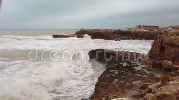 沿着海岸线向高大的岩石撞击海浪视频的预览图