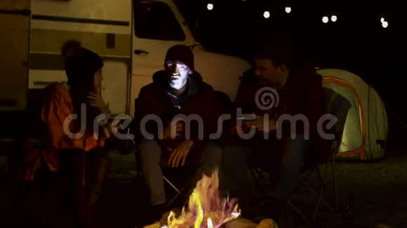 一个留胡子的人在篝火旁给他的朋友们讲一个可怕的故事视频的预览图